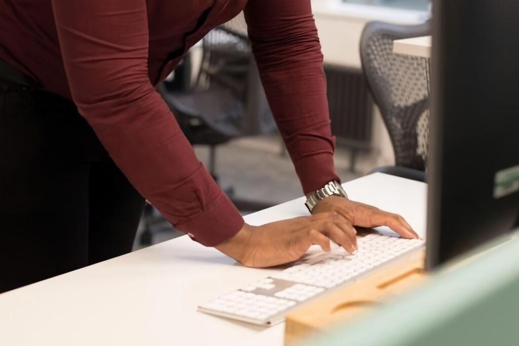 A person typing on a computer keyboard, focused on implementing Knowledge Management Systems in daily operations.
